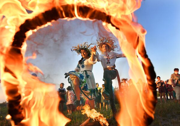 Девушка и юноша прыгают через огонь на празднике Ивана Купалы на берегу залива Припяти в древнем белорусском Турове - Sputnik Азербайджан
