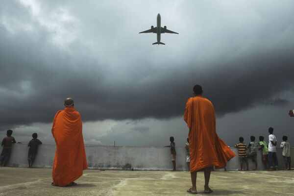 Буддийские монахи и дети наблюдают за взлетом самолета из международного аэропорта имени Нетаджи Субхас Чандра Боса в Калькутте - Sputnik Азербайджан
