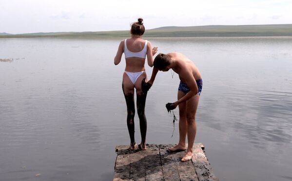 Мужчина намазывает девушку сульфидной грязью из озера Тус в Ширинском районе Республики Хакасия - Sputnik Азербайджан
