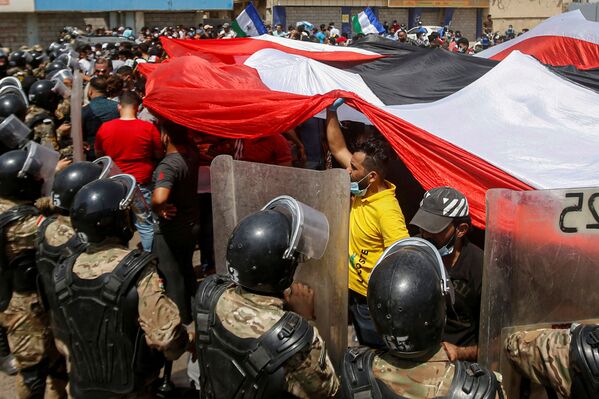 Iraqi security forces stand in front of demonstrators in anti-government protests during Iraqi Prime Minister Mustafa al-Kadhimi's visit, in Basra, Iraq, July 15, 2020.  - Sputnik Азербайджан