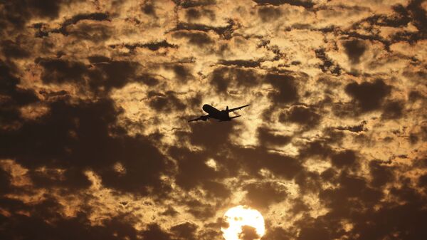 Силуэт самолета на фоне пылающих в заходящем солнце облаков в Ахмедабаде, Индия - Sputnik Азербайджан