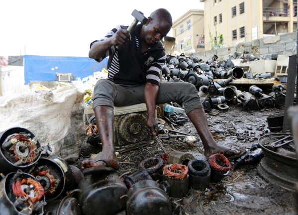 Мужчина работает над выброшенными компрессорами в центре по переработке в Абудже, Нигерия - Sputnik Азербайджан