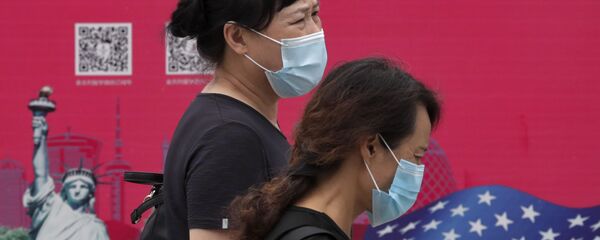 Женщины в защитных масках проходят мимо рекламного щита в Пекине Женщины в защитных масках проходят мимо рекламного щита в Пекине - Sputnik Азербайджан