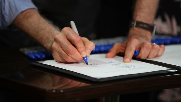 Мужчина ставит подпись на документе, фото из архива - Sputnik Азербайджан