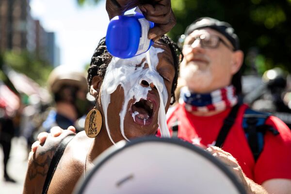 Девушке промывают глаза молоком во время акции протеста в Портленде, США - Sputnik Азербайджан