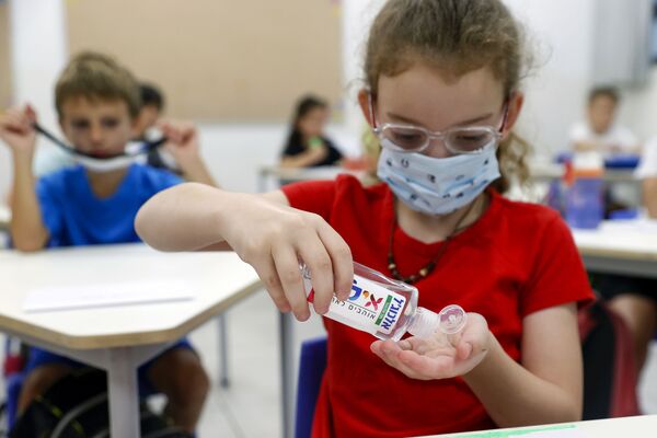 An Israeli girl, wearing a protective mask, applies disinfectant on her hands during the first day of school, during the coronavirus pandemic, in the Israeli coastal city of Tel Aviv on September 1, 2020.  - Sputnik Azərbaycan