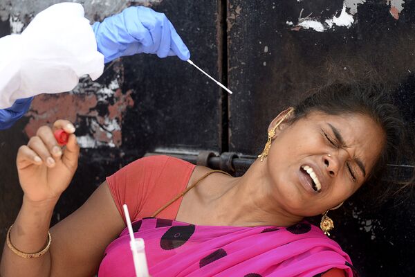 Медицинский работник берет образец мазка у женщины для проверки на Covid-19 в в жилом районе Ченнаи, Индия - Sputnik Azərbaycan