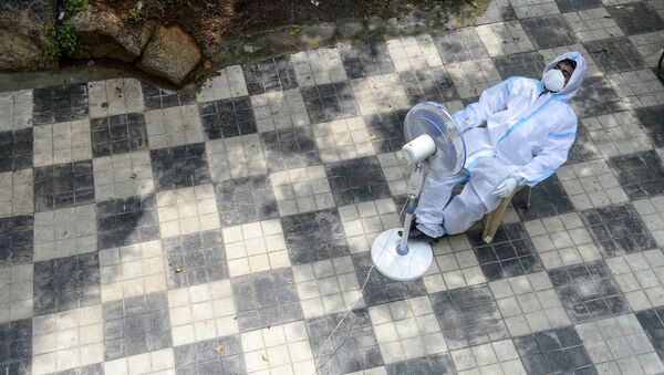 Медицинский работник отдыхает, ожидая сбора мазков для тестов на коронавирус в центре общественного здравоохранения в Хайдарабаде  - Sputnik Azərbaycan