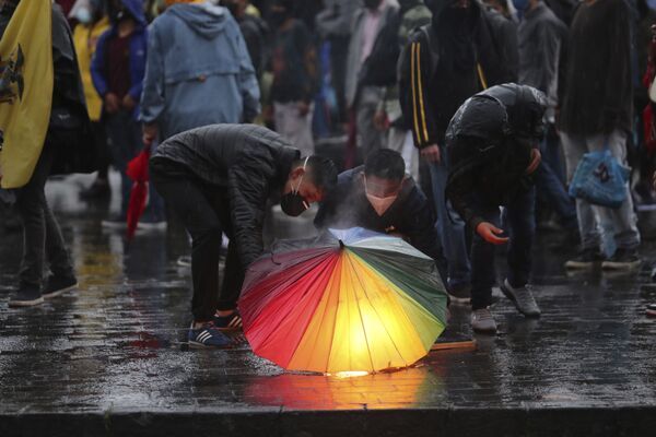 Демонстранты держат факел под зонтом во время акции протеста против экономической политики правительства Эквадора - Sputnik Azərbaycan