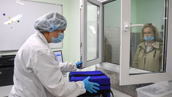 Лаборант принимает термосумку с биоматериалом, фото из архива - Sputnik Азербайджан