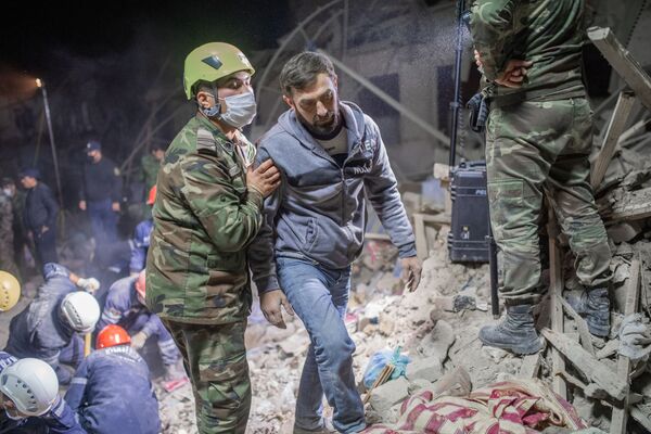 Спасатель МЧС АР вместе местным жителем ищет его родных после ракетного удара ВС Армении по азербайджанскому городу Гянджа - Sputnik Azərbaycan