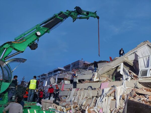 Местные жители и официальные лица ищут выживших в обрушившемся здании после сильного землетрясения в Измире  - Sputnik Azərbaycan