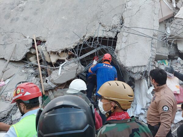 Местные жители и официальные лица ищут выживших в обрушившемся здании после сильного землетрясения в Измире  - Sputnik Азербайджан