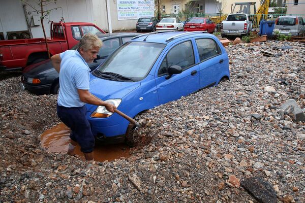 Мужчина выкапывает свою машину после проливных дождей в Малье на острове Крит, Греция - Sputnik Азербайджан