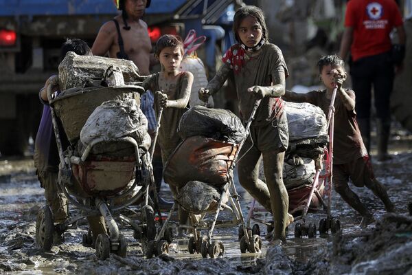 Дети везут коляски с вещами в деревне, пострадавшей от тайфуна Vamco на Филиппинах - Sputnik Азербайджан
