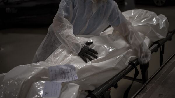Работник похоронного бюро перемещает тело человека, умершего от COVID-19, в морг  - Sputnik Azərbaycan