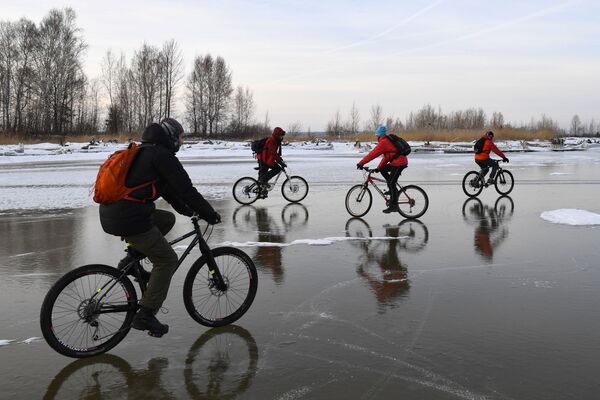 Велосипедисты катаются по льду водохранилища Новосибирской ГЭС возле острова Тань-Вань - Sputnik Азербайджан
