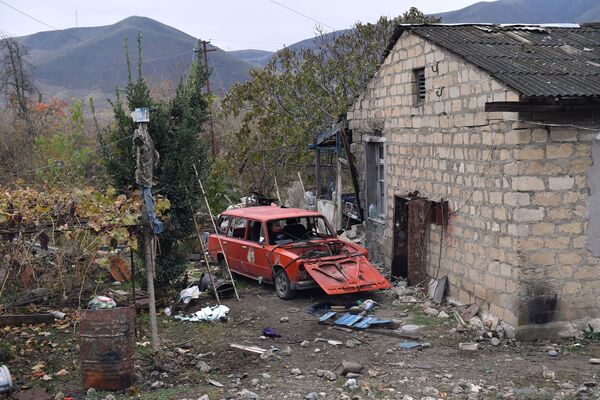 Автомобиль во дворе жилого дома в селе Суговушан, поврежденного в результате обстрела - Sputnik Азербайджан