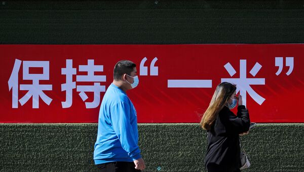 Люди в защитных масках проходят мимо рекламного щита в Пекине, фото из архива - Sputnik Azərbaycan