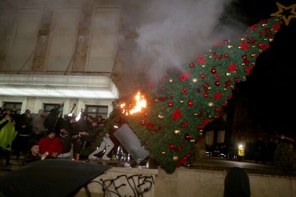 Протестующие сжигают рождественскую елку перед зданием премьер-министра Албании во время столкновений в Тиране - Sputnik Азербайджан