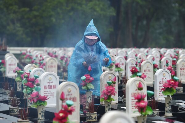 Посетитель зажигает ароматические палочки на кладбище мучеников Truong Son, Вьетнам - Sputnik Азербайджан