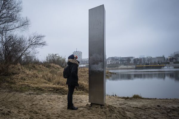 Женщина у металлического монолита, появившийся на берегу Вислы в столице Польши Варшаве - Sputnik Азербайджан