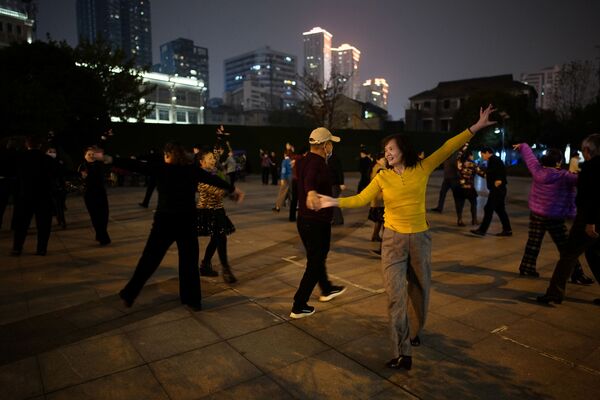 Люди танцуют ночью парке спустя год после вспышки COVID-19 в Ухане - Sputnik Azərbaycan