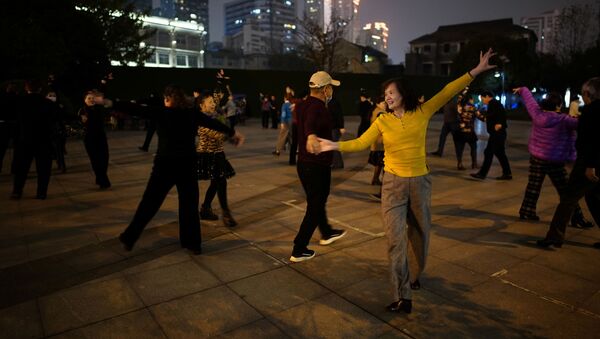 Люди танцуют ночью парке спустя год после вспышки COVID-19 в Ухане - Sputnik Azərbaycan