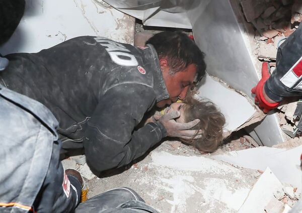 Турецкие спасатели вытаскивают ребенка из под обломков после землетрясения в Измире - Sputnik Азербайджан