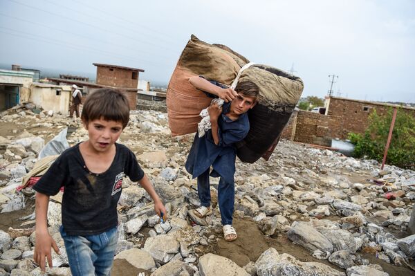 Молодые люди спасают остатки вещей из развалин домов после внезапного наводнения в Чарикаре, провинция Парван, Афганистан - Sputnik Azərbaycan