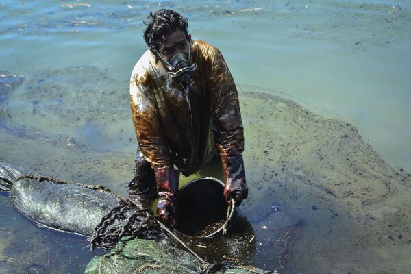 Мужчина очищает воду от разлившейся у берегов Маврикия нефти - Sputnik Azərbaycan