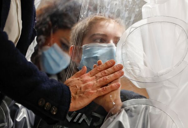 Госпитализированный с COVID-19 ребенок касается руки своего отца через пластиковую защиту в отделении детской больницы в Риме, Италия - Sputnik Азербайджан