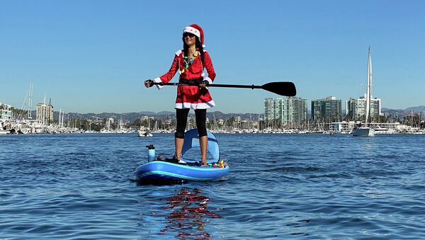 Девушка в костюме Санта-Клауса на SUP-серфе в Лос-Анджелесе, Калифорния - Sputnik Азербайджан