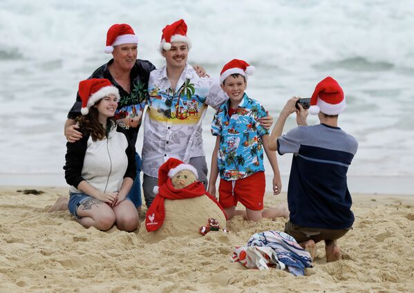 Семья в рождественских колпаках фотографируется на пляже в Сиднее, Австралия  - Sputnik Azərbaycan