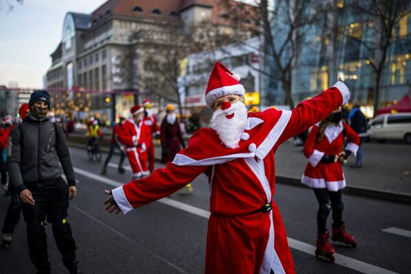 Люди в костюмах Санта-Клауса на роликовых коньках и велосипедах во время шествия в Берлине - Sputnik Азербайджан