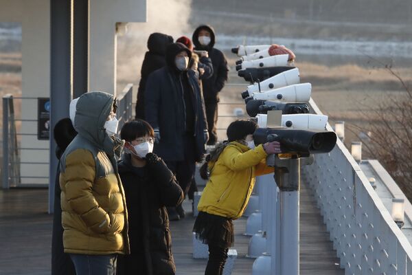 Люди в защитных масках у биноклей недалеко от границы с Северной Кореей, Южная Корея - Sputnik Азербайджан