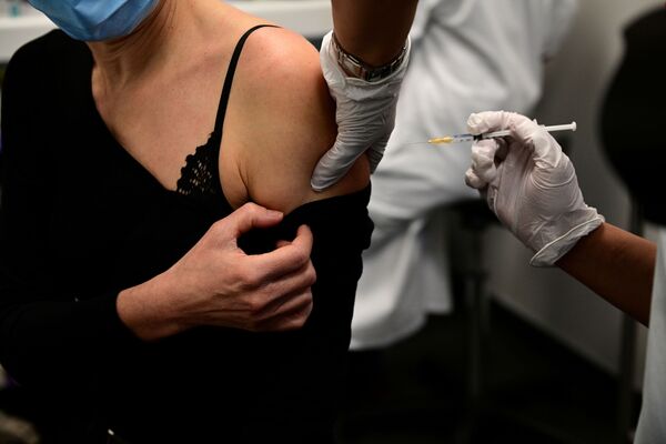 Женщина получает вакцину от COVID-19 во время кампании вакцинации медицинских работников в центре вакцинации в Париже - Sputnik Азербайджан