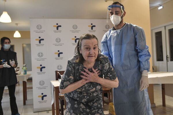 Женщина выражает благодарность после вакцинации от Covid-19 в доме престарелых в пригороде Афин, Греция - Sputnik Azərbaycan