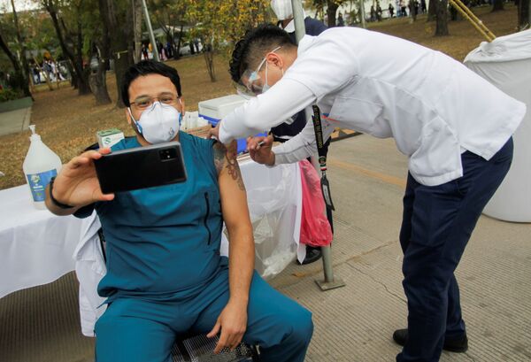 Медицинский работник делает селфи во время инъекции вакцины отCOVID-19 в военном госпитале в Сан-Николас-де-лос-Гарса, Мексика - Sputnik Азербайджан