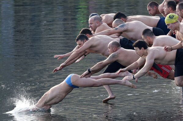 Мужчины прыгают в озеро, чтобы поймать деревянный крест во время празднования Дня Крещения в Софии, Болгария - Sputnik Azərbaycan
