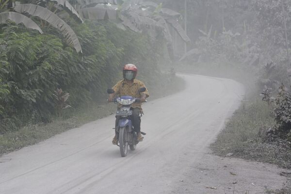 Мужчина во время проезда по покрытой пеплом улице после извержения вулкана Семеру в Индонезии  - Sputnik Azərbaycan