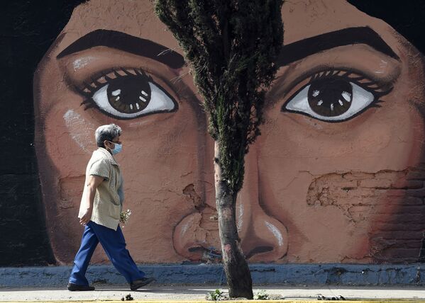 Женщина  проходит мимо граффити на одной из стен кладбища San Nicolas Tolentino в муниципалитете Истапалапа в Мехико - Sputnik Азербайджан