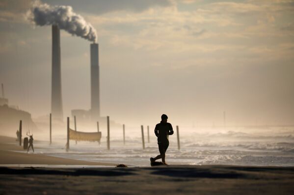 Мужчина бежит по пляжу в Ашкелоне во время третьего локдауна в Израиле - Sputnik Азербайджан