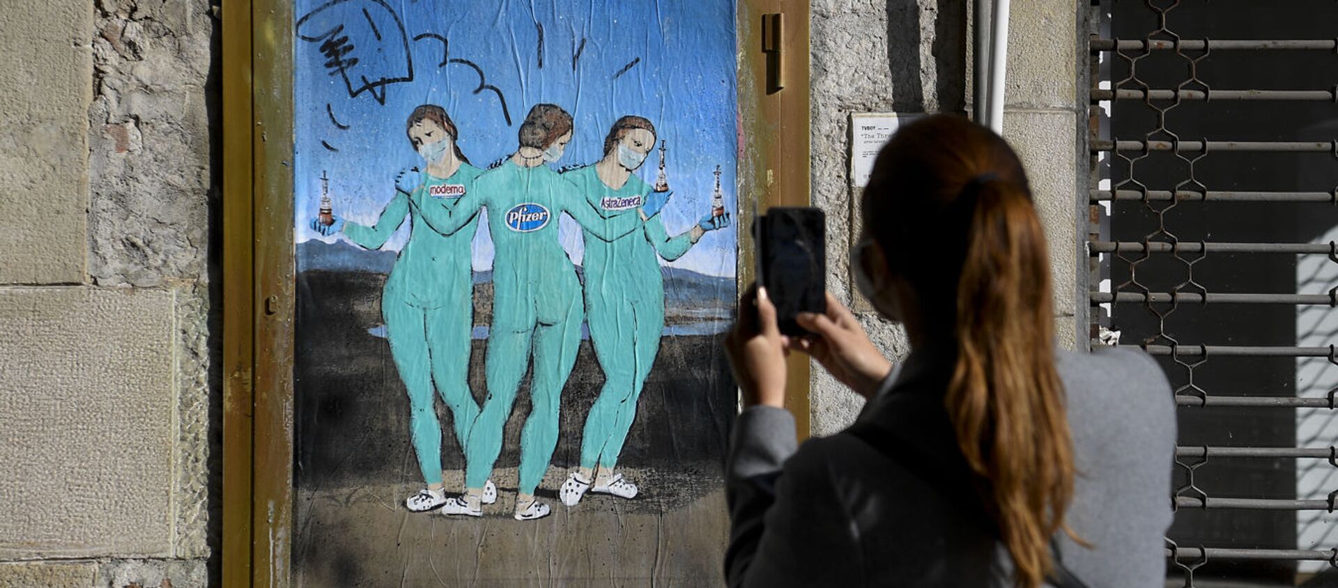 Женщина фотографирует на свой мобильный телефон новую работу итальянского уличного художника TvBoy под названием «Три вакцины», на которой изображена картина итальянского художника Рафаэля «Три грации», в Барселоне, 19 января 2021 года - Sputnik Азербайджан, 1920, 25.01.2021