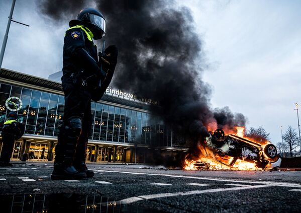 Горящий автомобиль перед железнодорожным вокзалом в Эйндховене, подожженный во время протестов в Нидерландах - Sputnik Azərbaycan