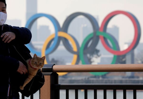 Мужчина с котом в сумке на фоне олимпийских колец в Токио - Sputnik Azərbaycan