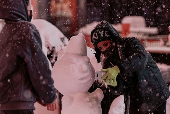 Женщина делает селфи со снеговиком на Таймс-сквер во время снегопада в Нью-Йорке - Sputnik Азербайджан