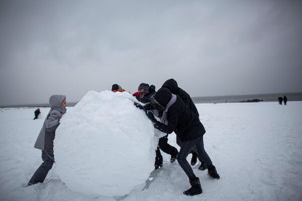 Люди лепят гигантский снежный шар во время сильного снегопада на Брайтон-Бич, Нью-Йорк - Sputnik Азербайджан