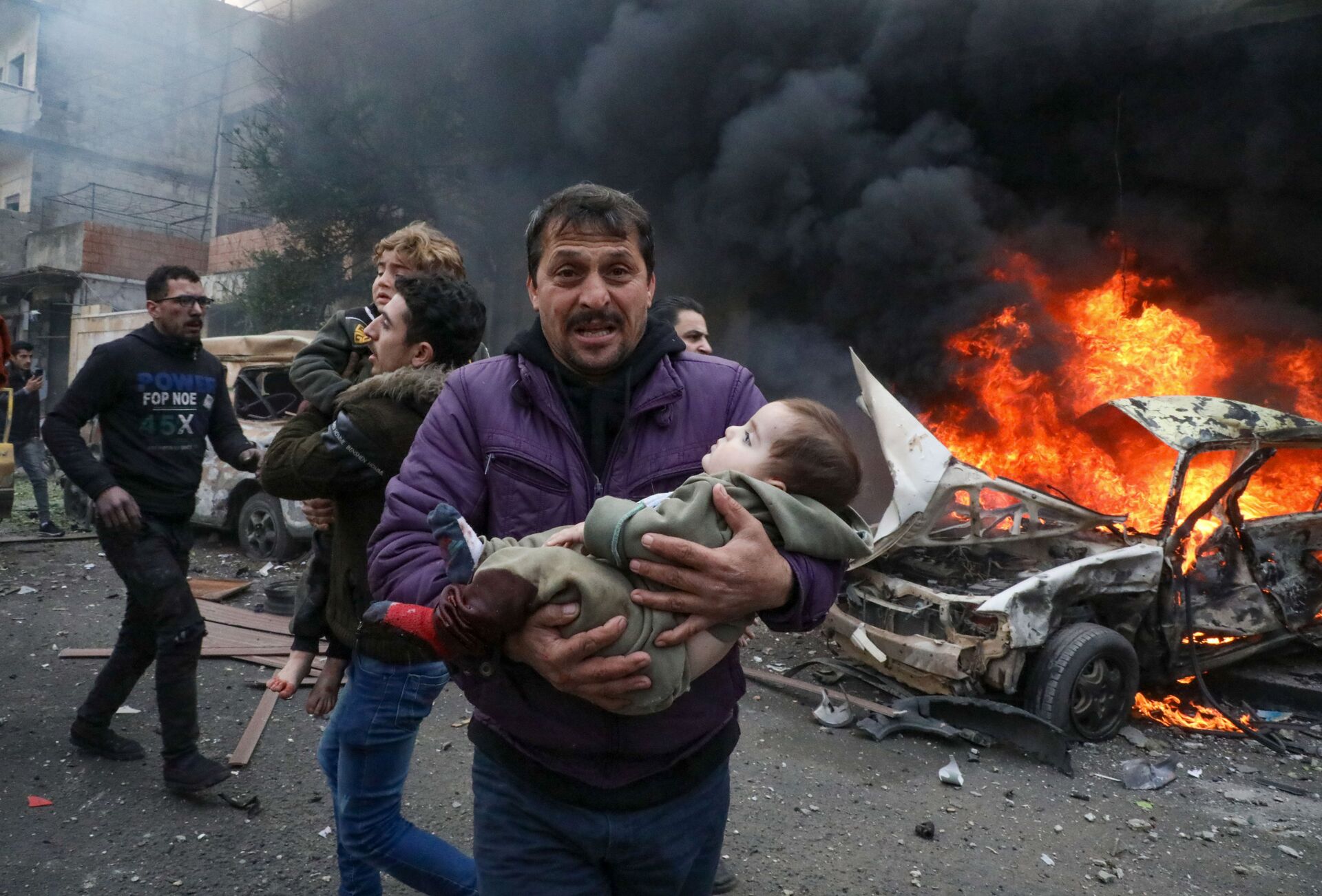 Мужчина несет на руках ребенка, пострадавшего в результате взрыва заминированного автомобиля в сирийском городе Азаз - Sputnik Azərbaycan, 1920, 22.11.2022