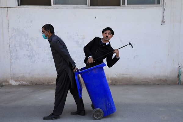 Мужчина в костюме Чарли Чаплина в мусорном баке во время представления в Пешаваре, Пакистан - Sputnik Азербайджан